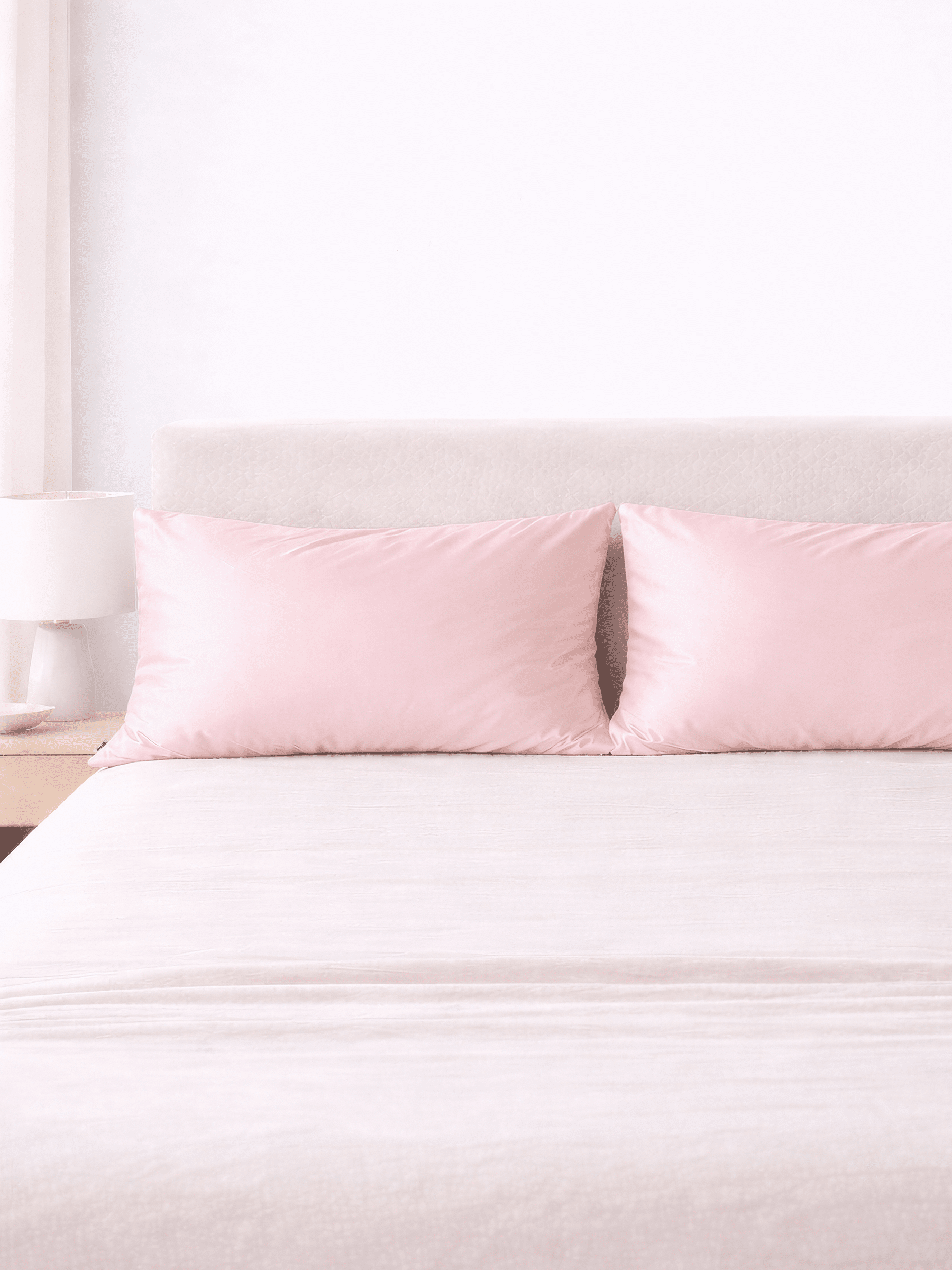 two pink king size silk pillowcases sitting on bed