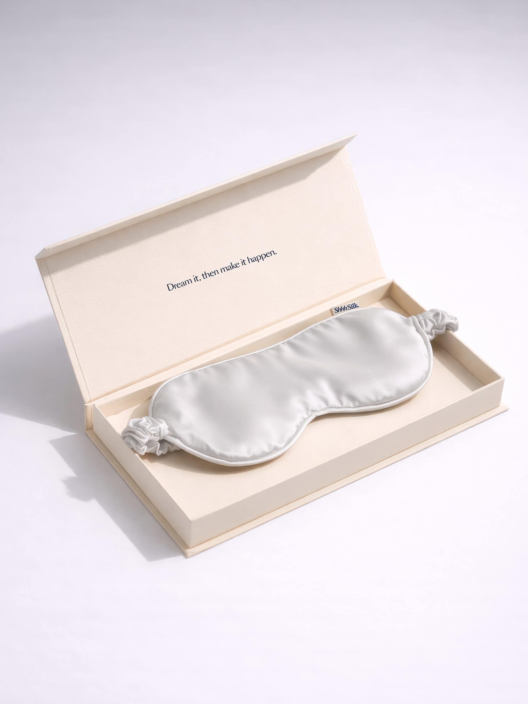 Grey silk sleep mask in a decorative box with a quote on a light background