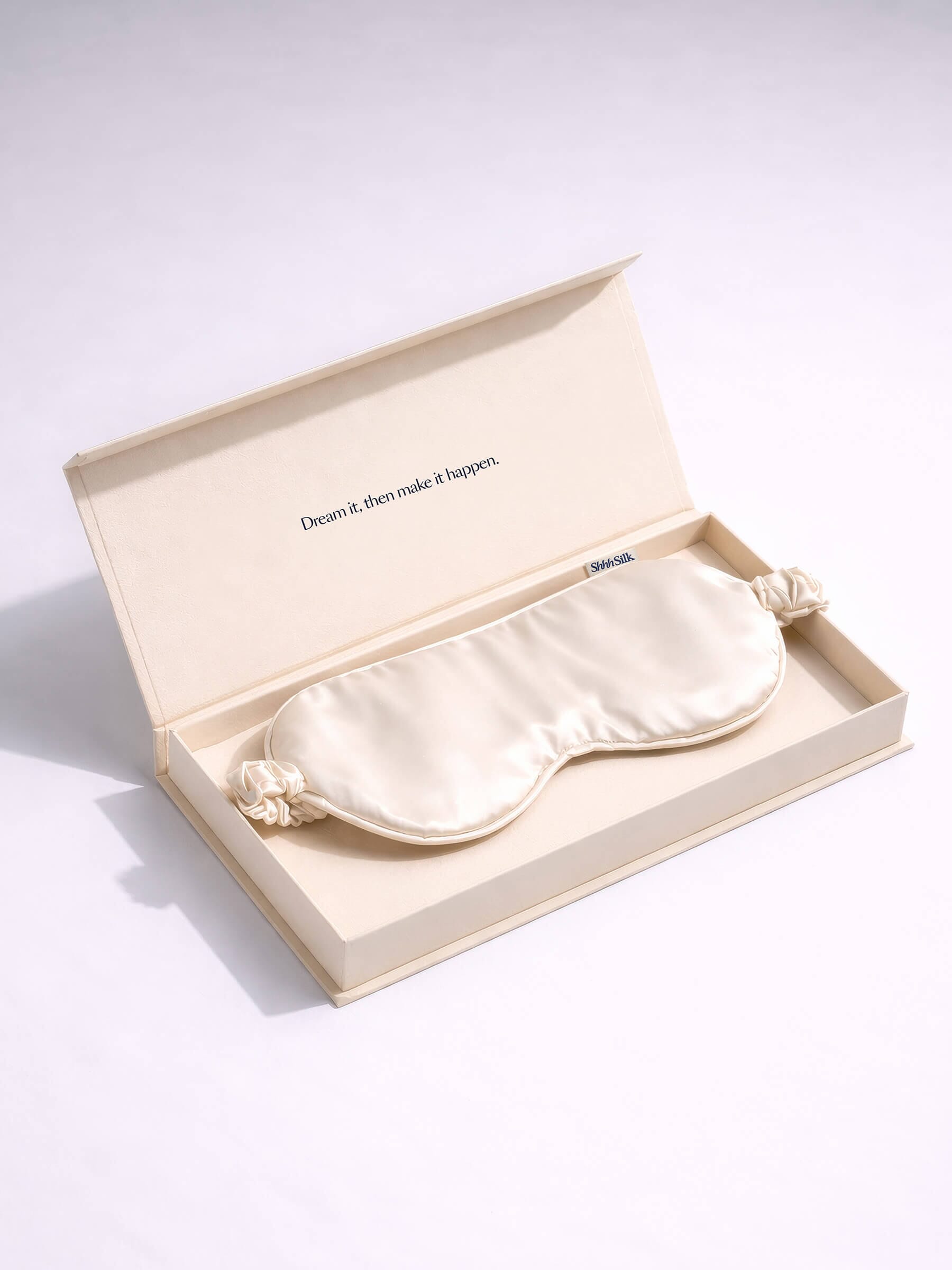 White silk sleep mask in a beige box on a light grey background