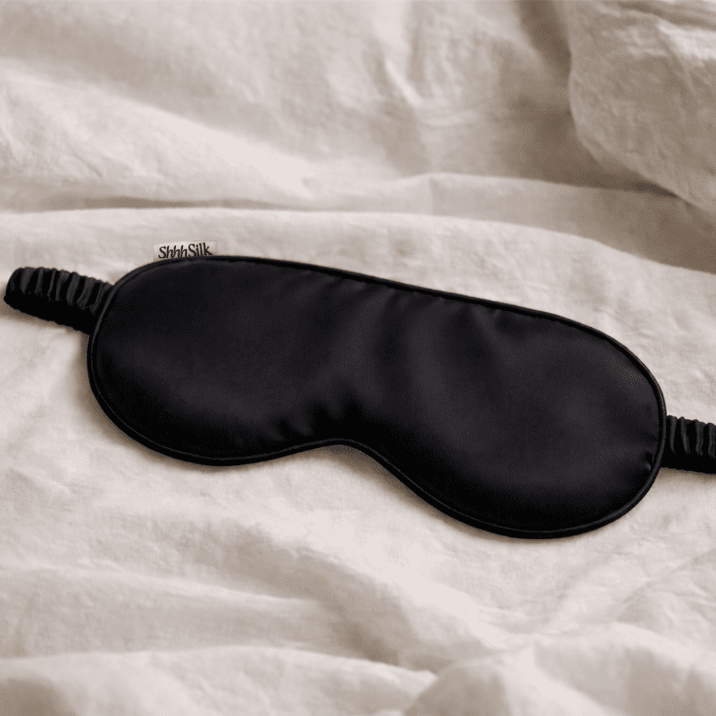Black silk sleep mask on a white textured surface