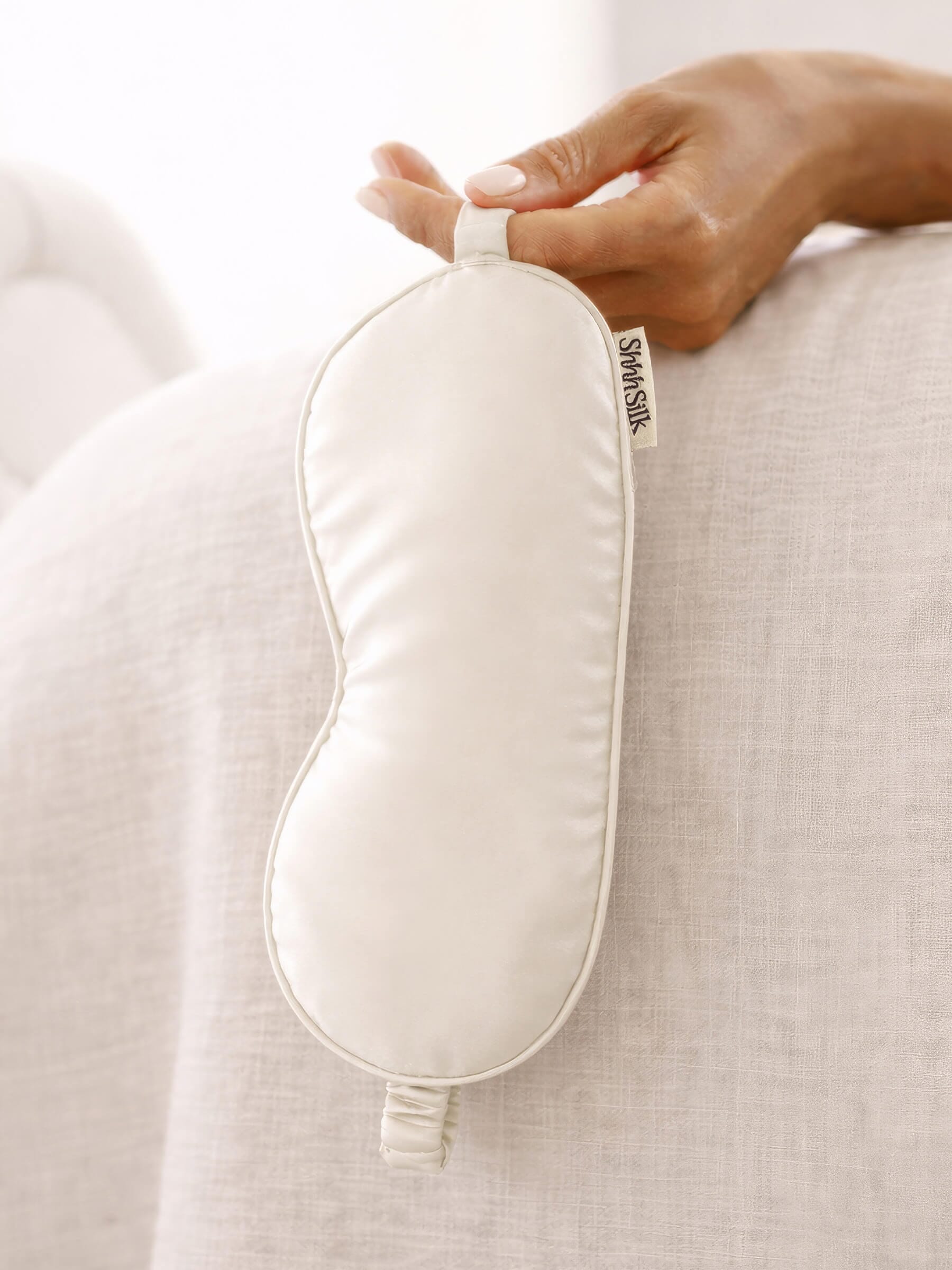 White silk sleep mask on a soft fabric background
