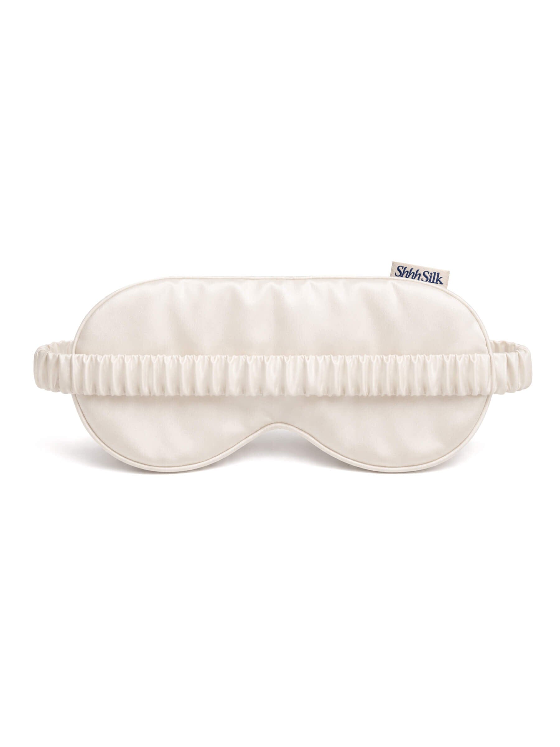 White silk sleep mask with a brand label on a white background